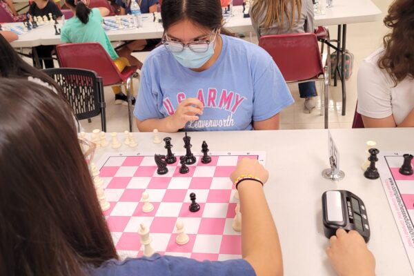 Girl scout playing chess on a pink chess board